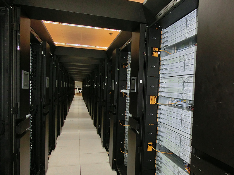 > The whole cluster system is composed of 170 racks, using multiple matrix layout, covers an area of 5000 square meters, the overall image is magnificent. The front door of the frame is made of acrylic mirror material with simple appearance. The whole row of devices is decorated with blue light strips, indicating speed and a sense of space.